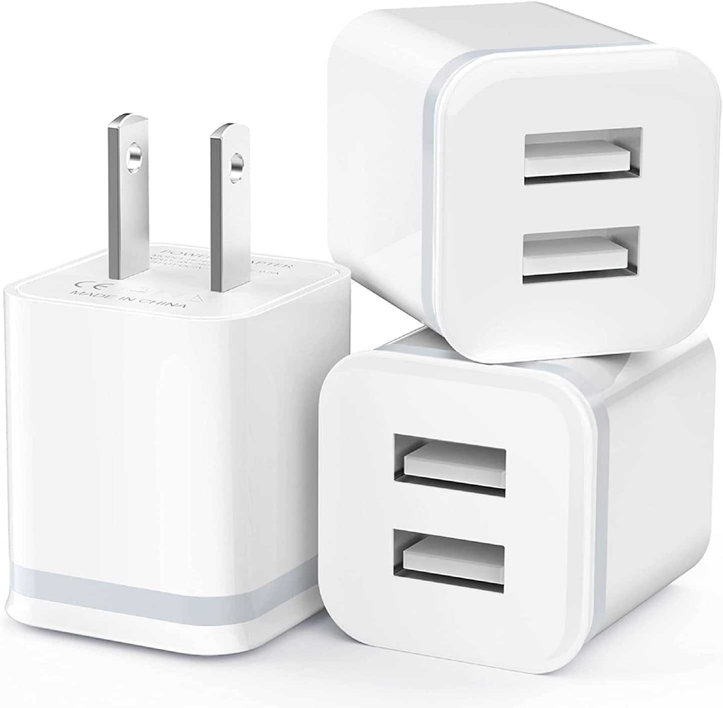 Three white USB wall chargers with dual ports and flat-pin plugs stacked together.