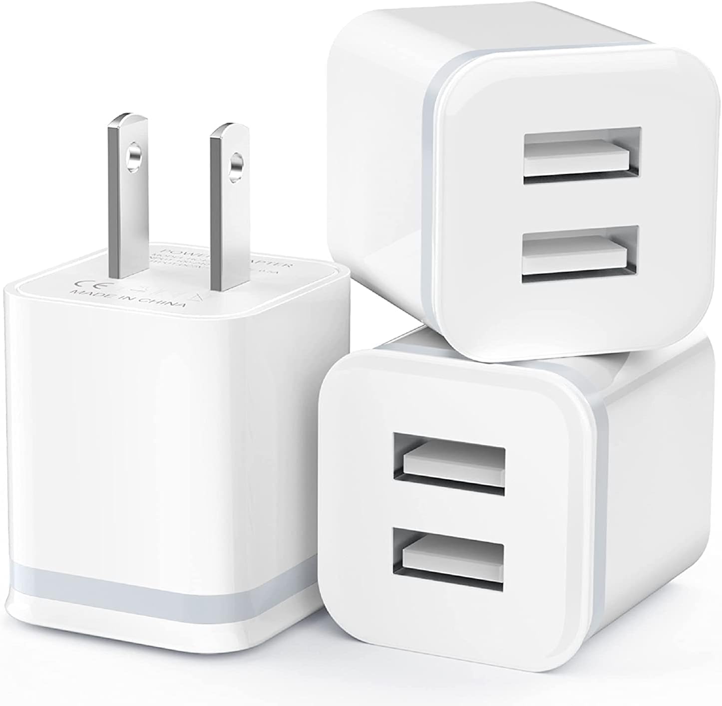 Three white USB wall chargers with dual ports and flat-pin plugs stacked together.