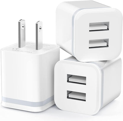 Three white USB wall chargers with dual ports and flat-pin plugs stacked together.