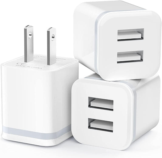 Three white USB wall chargers with dual ports and flat-pin plugs stacked together.