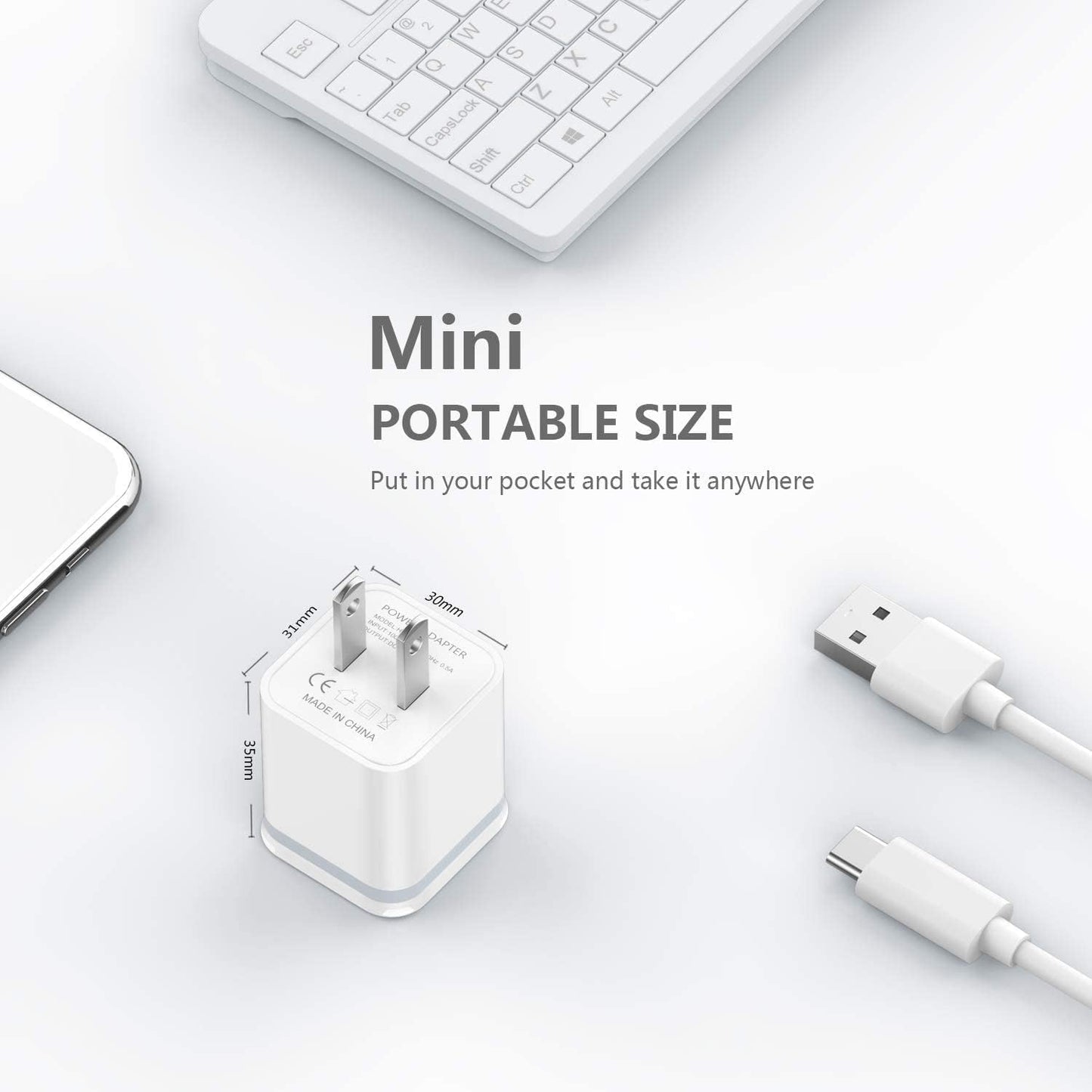 White mini USB charger with dimensions, surrounded by a keyboard, phone, and cables.