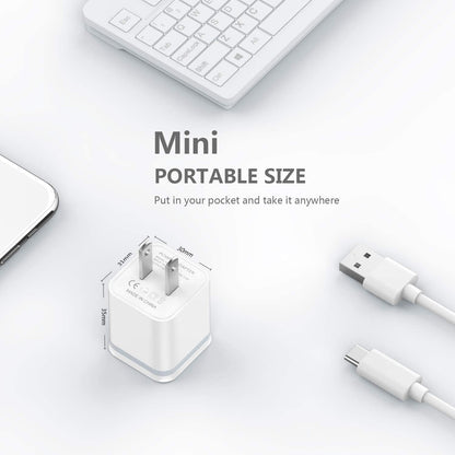 White mini USB charger with dimensions, surrounded by a keyboard, phone, and cables.